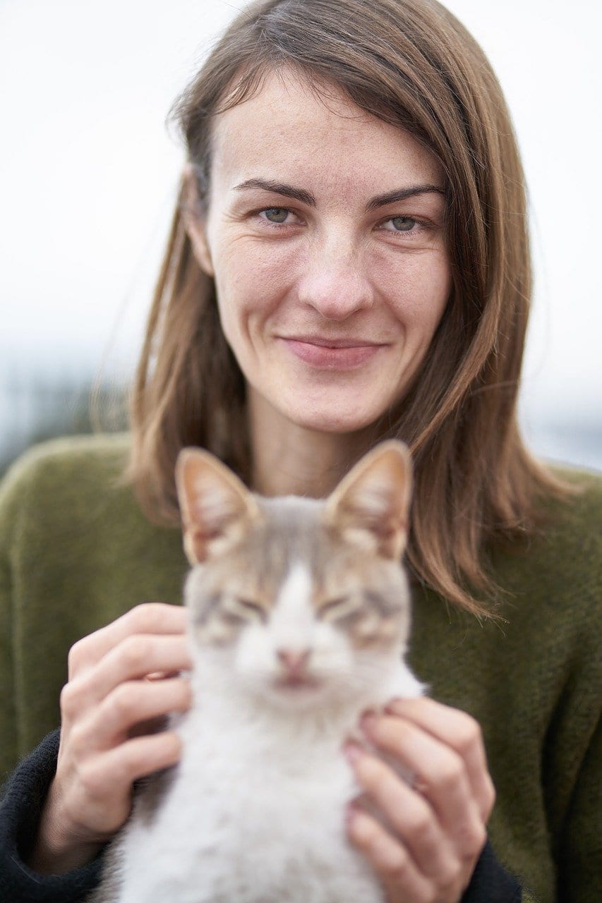 An image of a woman holding a white cat.